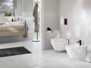 Helles Badezimmer mit Waschtisch, aufgesetztem Waschbecken, WC und Bidet mit schwarzen Armaturen und Halterungen von Grohe.