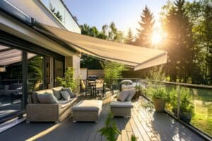 Eine großzügige Terrasse mit Loungebereich, Kaffeetisch, Gasgrill Terrassenschiebetüren mit schwarzem Alu-Rahmen und einer wandmontierten, geneigten beigen Markise in XXL von Haderer.