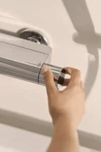 HANSA zeigt den Drehregler mit Thermostat der verchromten glänzenden Wandarmatur Viva.