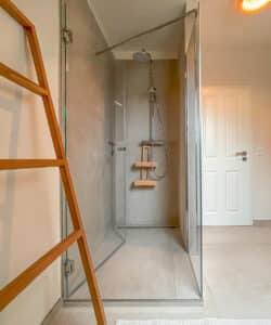 Hansa zeigt eine Regendusche und eine Handdusche, beide mit rundem Kopf und in silber, in einem Badezimmer eines Hotels.