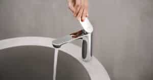 Hansa präsentiert eine elegante Armatur in silber mit obenliegendem Hebel, am Beckenrand montiert, bei der das Wasser aufgedreht wird.