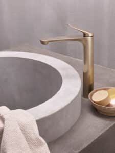 Hansa präsentiert eine elegante Armatur in gold mit obenliegendem Hebel und freistehend neben dem Beckenrand in einer Nahaufnahme.