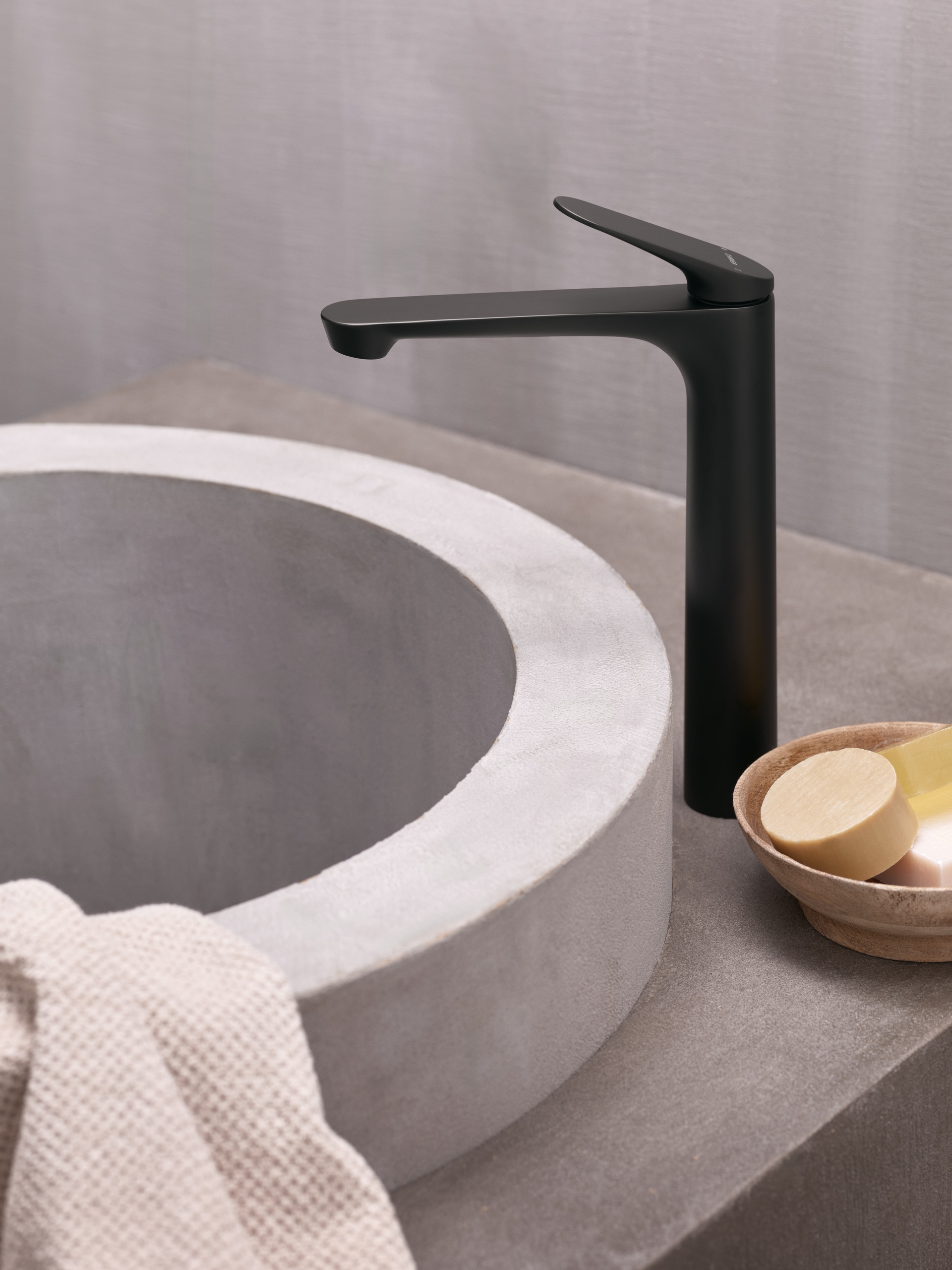 Hansa präsentiert eine elegante Armatur in schwarz mit obenliegendem Hebel und freistehend neben dem Beckenrand.