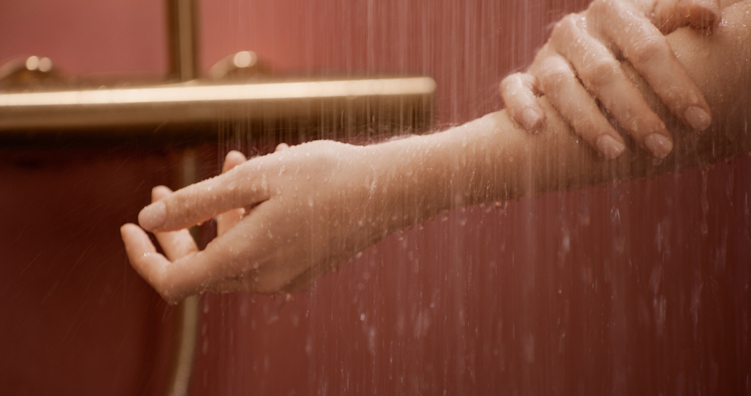 Hansa zeigt eine Frau, die sich den Arm wäscht in einer Dusche mit messingfarbener Wandarmatur.