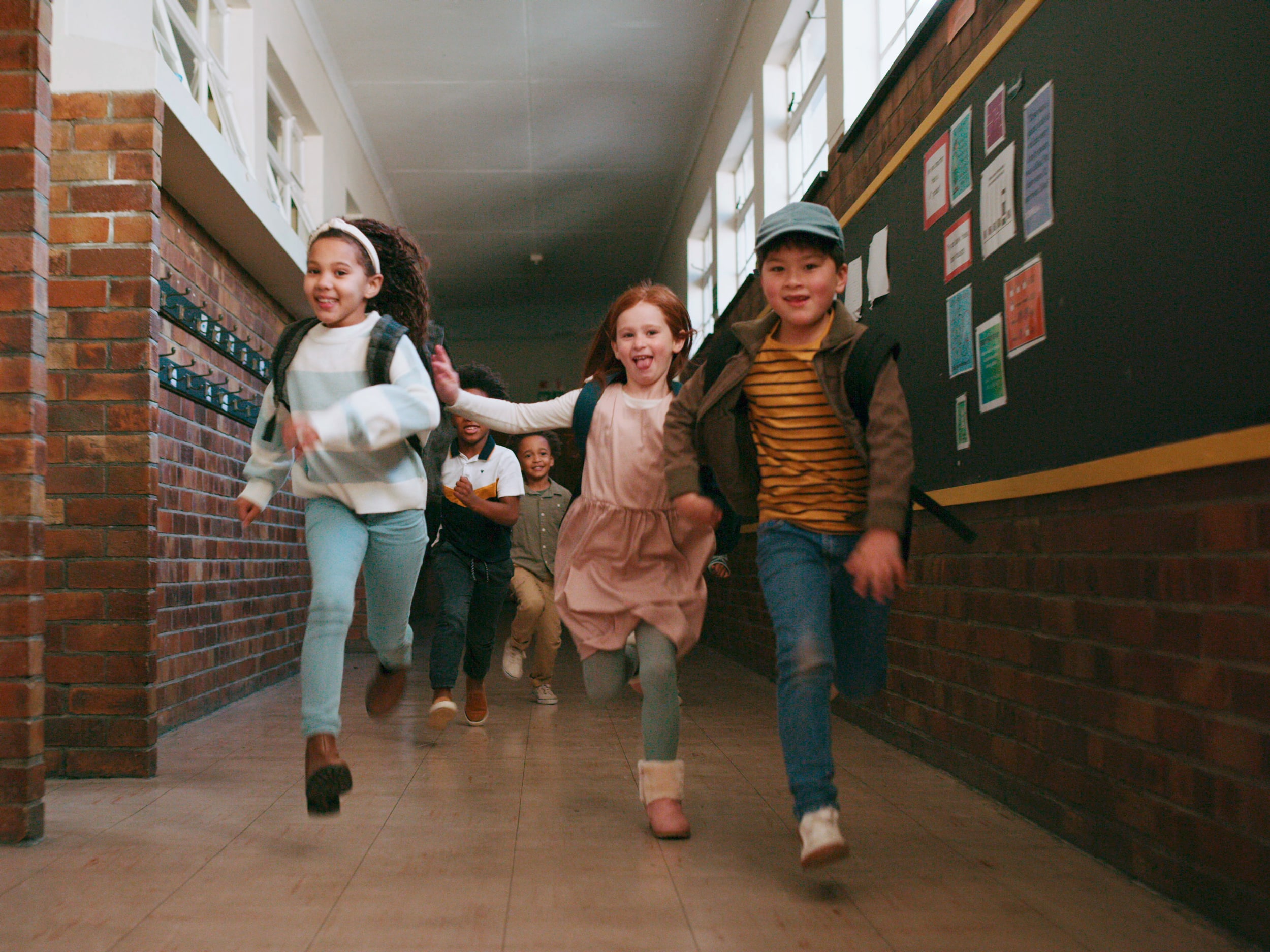 Kinder laufen glücklich durch einen Schulgang.