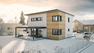 HARTL HAUS zeigt ein zweistöckiges Einfamilienhaus mit Flachdach und Dachvorsprung, eine anthrazitfarbene Pergola mit Lamellendach zur Überdachung der mit grauen Steinfliesen versehenen Terrasse und Eckfenster ummantelt mit einem Holzfassadenelement.