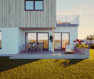 Ein Flachdachhaus mit Holz‑Elementfassade, Garten und überdachtem Terrassenbereich auf Holzpodest von HARTL HAUS.