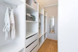 Ein begehbarer Kleiderschrank bzw. Ankleidezimmer mit weißen Regalen und viel Stauraum von HARTL HAUS.