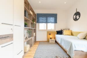 Ein Gäste- bzw. Jugendzimmer mit Bett, Regal, Schrank und Einzelbett bzw. Sitzbereich von HARTL HAUS.
