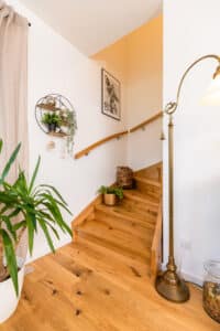 Eine Holztreppe mit Handlauf und dekorativer Einrichtung in einem hellen Wohnbereich, von HARTL HAUS.