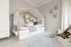 Ein liebevoll gestaltetes Kinderzimmer mit gemütlichem Bett mit verspielter Überdachung, einem Tipi und viel Spielzeug von HARTL HAUS.