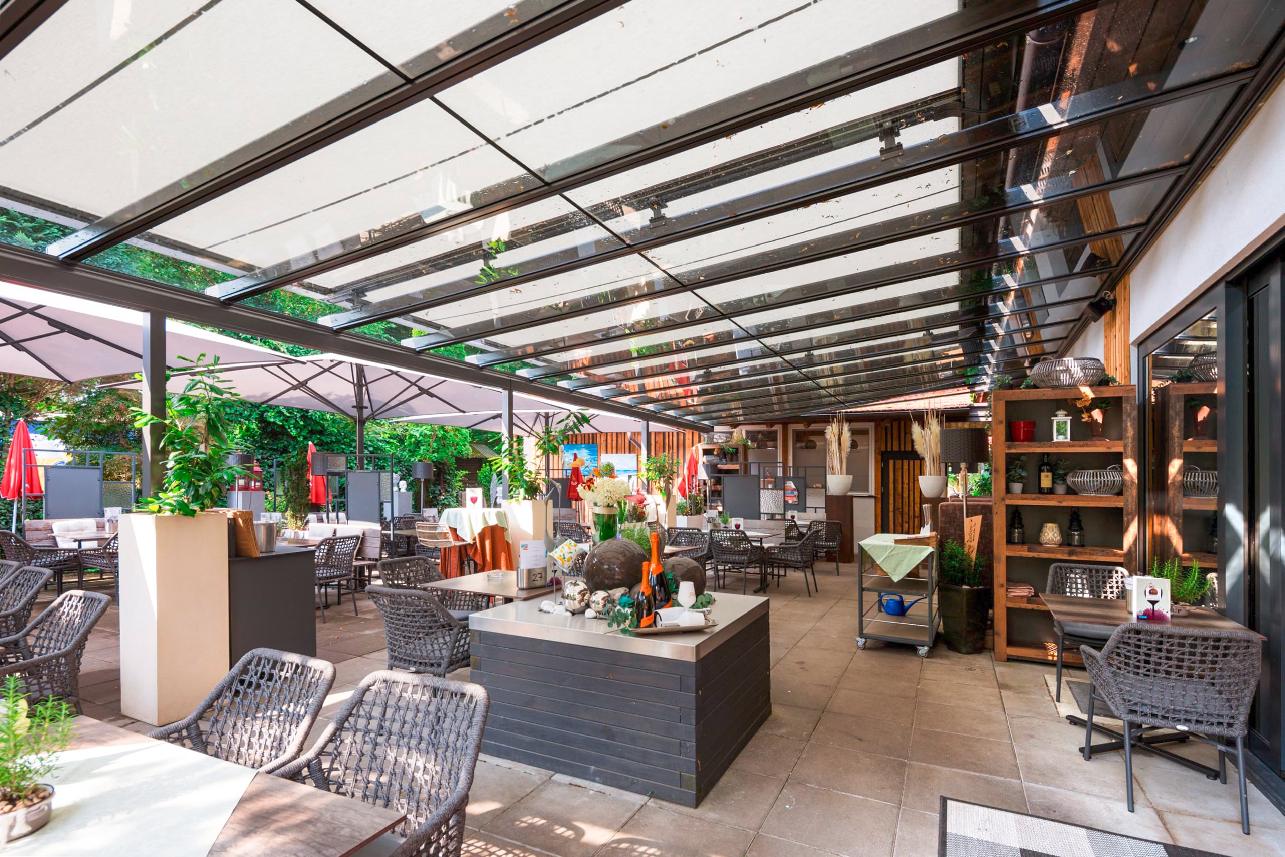 Ein Terrassenbereich mit Glasdach und aussenliegender ausgefahrener Textilmarkise zur flexiblen Beschattung von HELLSAN.