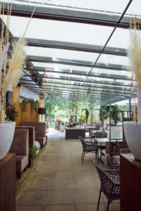 Detailaufnahme einer Anbaupergola mit schrägem Glasdach und integrierter Textilmarkise zur flexiblen Beschattung von HELLSAN.