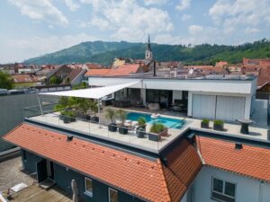 Ein modernes dreieckiges Sonnensegel mit Deckenhalterung in eleganter Draufsicht über Terrasse und Pool von SunFurl, gezeigt von HELLSAN.