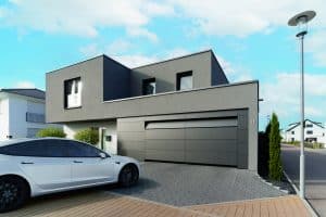 Modernes Flachdachhaus mit schwarzen Plattenfassadenelementen und passendem sektionalem Garagentor von Hörmann Austria.