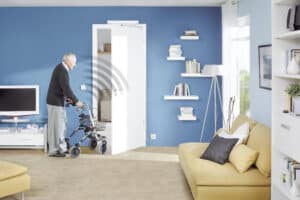 Ein Mann mit Rollator an einer barrierefreien, selbstöffnenden weißen Innentür von HÖRMANN mit automatischem Antrieb in einem modern eingerichteten Wohnbereich.