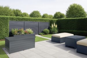 Moderne Gartenbox in Anthrazit - die sich nahtlos in das Design von Sichtschutz, Blumentrog und Outdoormöbeln einfügt - in einem begrünten Garten von HÖRMANN AUSTRIA.