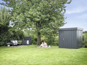 Obstgarten mit einer Juno Gartenbox und dem dazu passenden Gerätehaus mit Flachdach und bodentiefen Glaselementen in schwarzer Ausführung von HÖRMANN AUSTRIA.