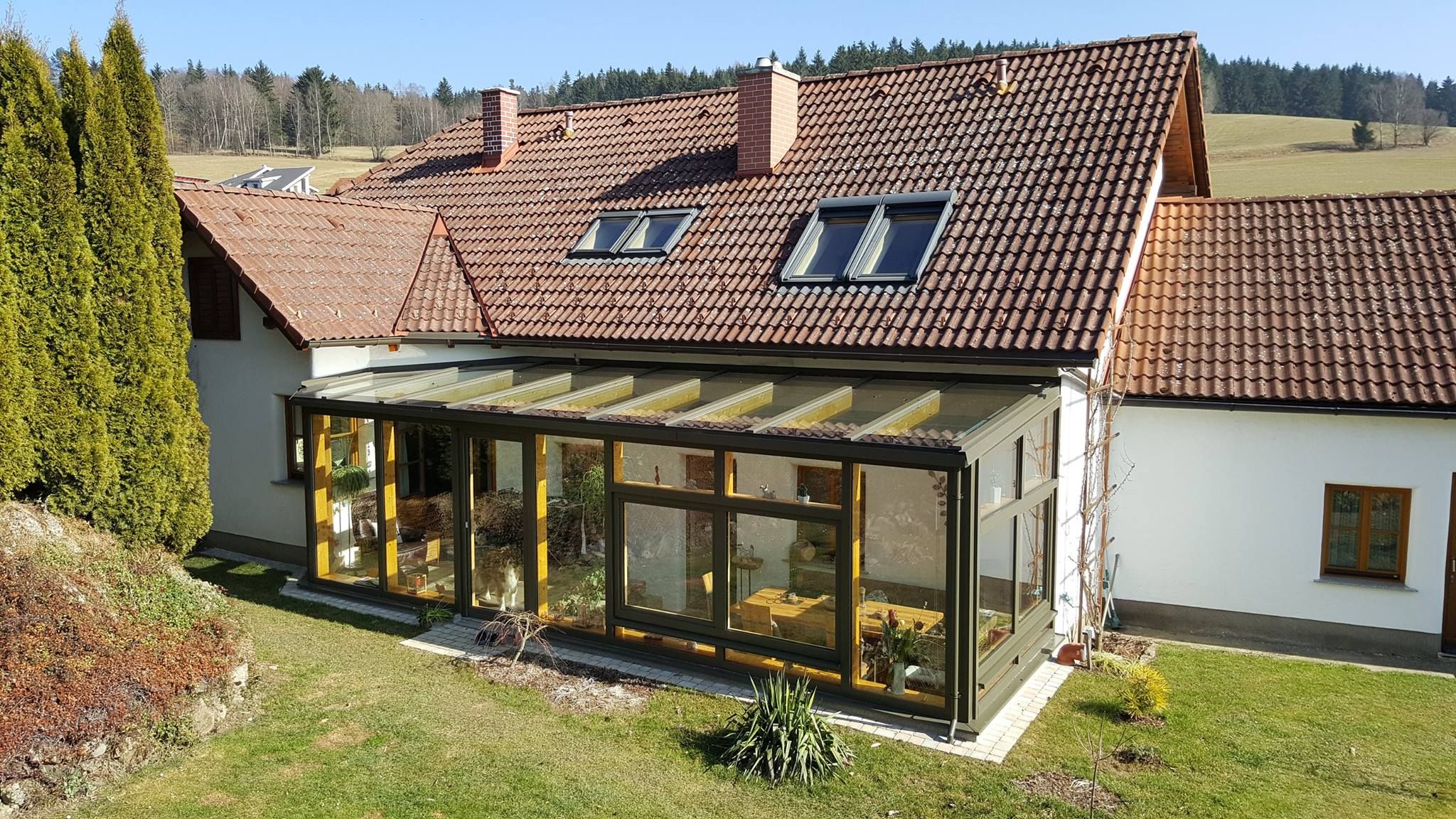 Einfamilienhaus mit angebautem Wintergarten aus Holz und Glas mit verglastem Pultdach von Glaserei Hohl.