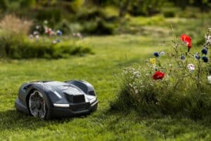 Der Mähroboter 410XE NERA von Husqvarna beim Mähen eines Anwesens mit wilder Blumenwiese.