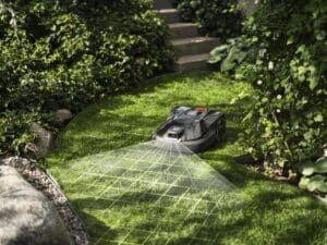 Ein Rasenroboter im Garten bei der Berechnung der Hürden und Begrenzungslinien ausgestattet mit Kamera und Licht von Husqvarna.