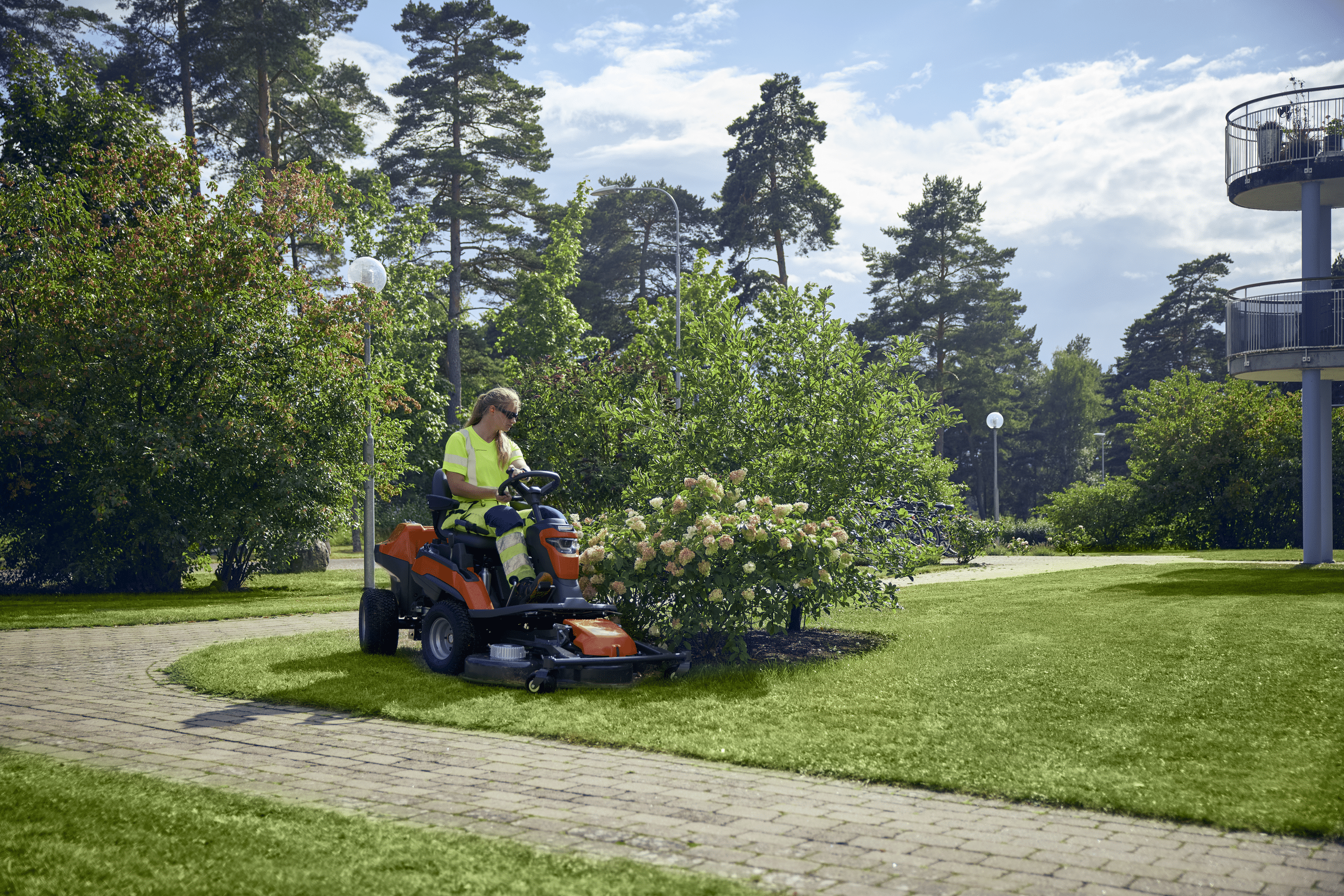 Husqvarna zeigt wie der Frontmäher FM 410i in einer Parkanlage von einer Landschaftspflegerin bedient wird.