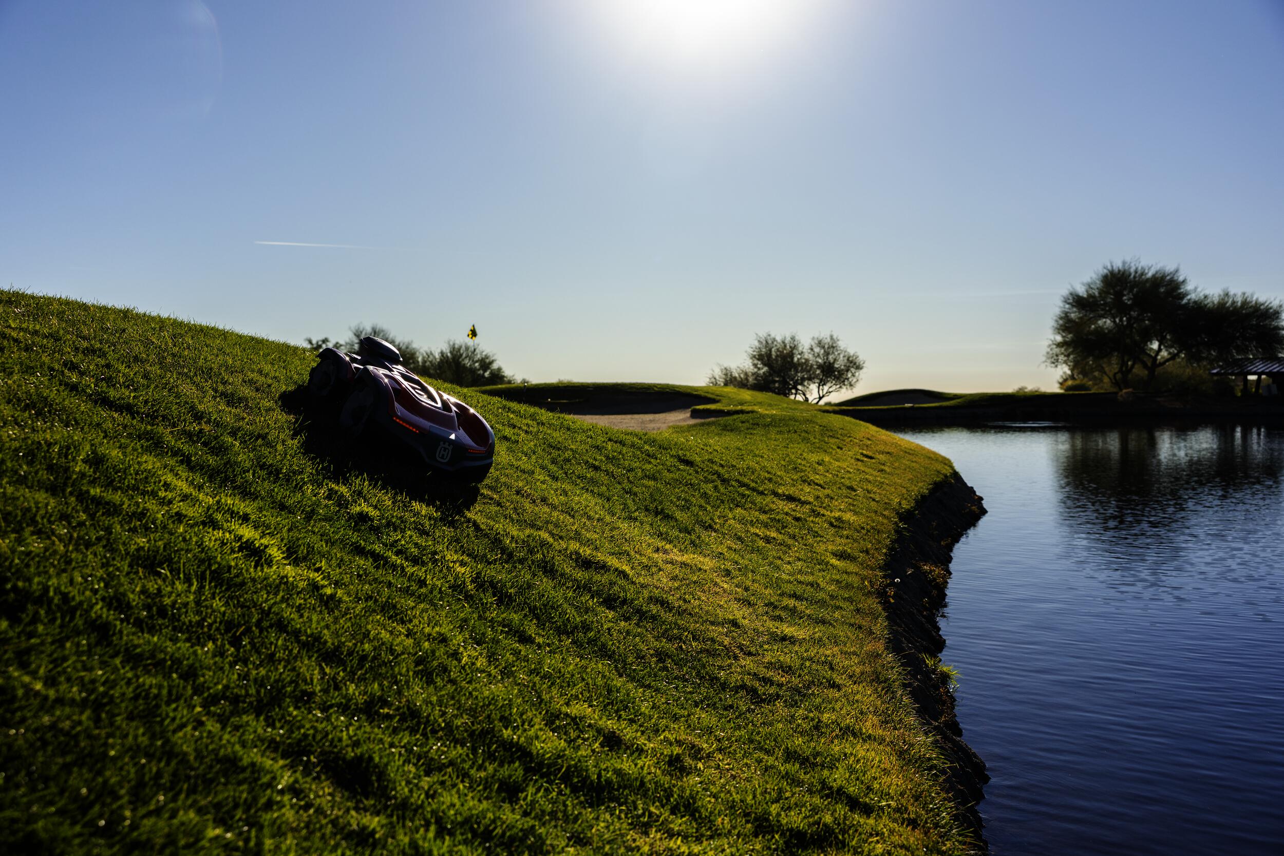 Husqvarna zeigt den Automower aus der 500er Serie auf einem Golfplatz mit Steigung, Sandloch und einem kleinen See.