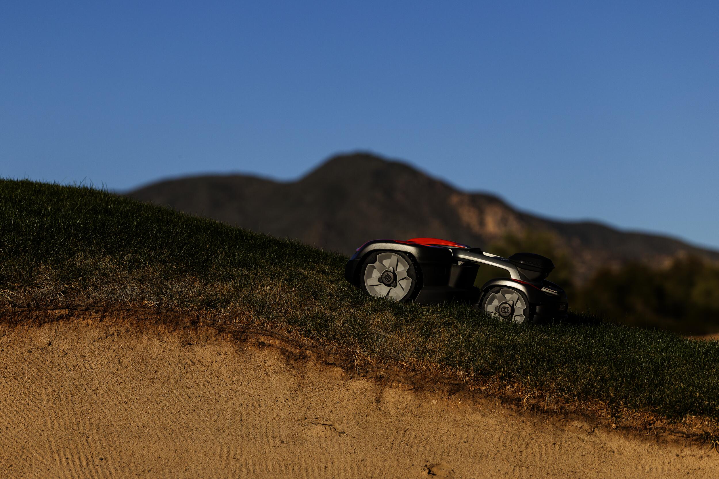 Husqvarna zeigt den Automower aus der 500er Serie auf einem Golfplatz mit Steigung und Sandloch.