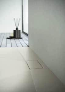 Beigefarbene, bodenebene Duschtasse mit dezent integrierter Abdeckung und sanfter Oberflächenstruktur von Disenia.