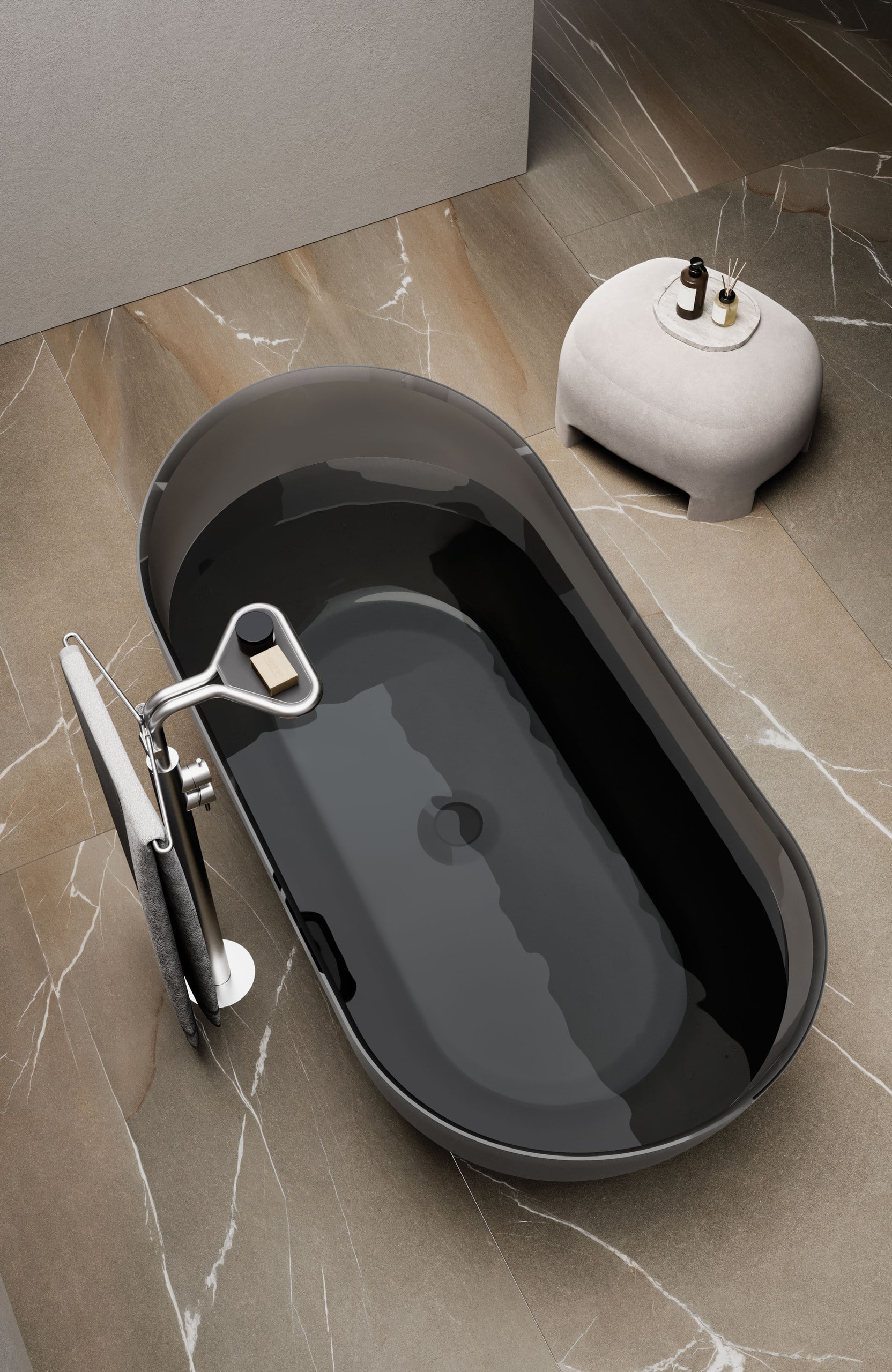 Freistehende ovale Badewanne aus halbtransparentem schwarzen Rauchglas, mittigem Ablauf, freistehender Chromarmatur mit Handtuchhalter und schwarzer Ablage, auf einem Fliesenboden in brauner Marmoroptik und einem Beistelltisch bzw. Hocker in Betonoptik von Disenia.