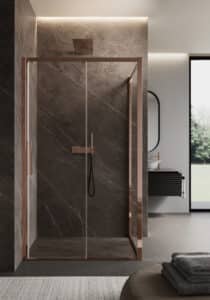 Ein Badezimmer mit Duschnische und zweiseitiger Verglasung, Glastür, kupferfarbenem Rahmenprofil, Türgriff, Regendusche, Handbrause und Armatur, Wände in graubrauner Marmoroptik und dahinter ein schwarzgeriffelter Waschtisch mit Spiegel von Disenia.