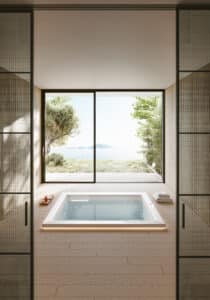 Der quadratische weiße Outdoor-Whirlpool "Gilium" mit beleuchtetem LED-Rand von Disenia - hier in der Unterbauversion in einem japanisch-minimalistisch gestalteten Haus mit barrierefreiem Terrassenzugang.