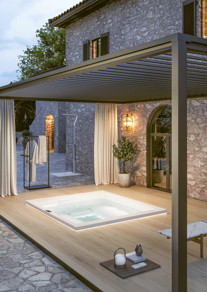 Eine Terrasse mit Pergola, seitlichen Vorhängen und Lamellendach und einer Unterbau-Version des Whirlpools "Helba 240" in Weiss mit Nackenstützen bzw. Einstiegshilfen oder Sitzflächen am Rand mit matter Oberfläche von Disenia.
