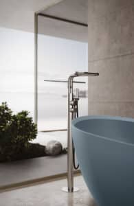 Disenia von Idea Group zeigt eine freistehende Badewannenarmatur in mattem silber mit Handdusche, Handtuschhalter und Ablagefläche.