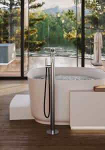 Disenia von Idea Group zeigt eine freistehende Badewannenarmatur in mattem silber mit Handdusche, Handtuschhalter und Ablagefläche.