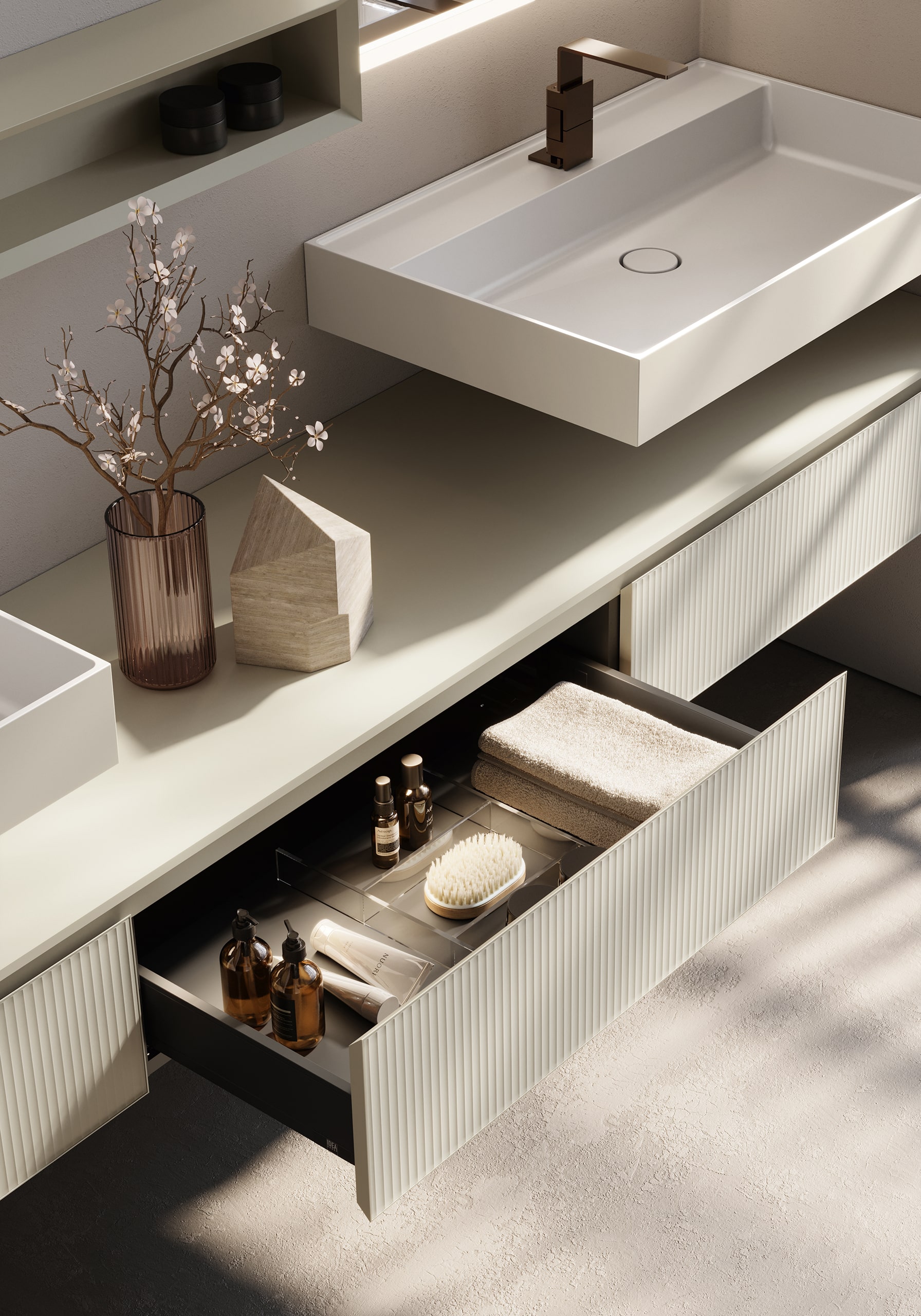 Idea Group präsentiert einen Waschtisch mit an der Wand montiertem weißen Waschbecken und weißem Unterschrank mit Längsrillen und geräumigen Auszugsladen.