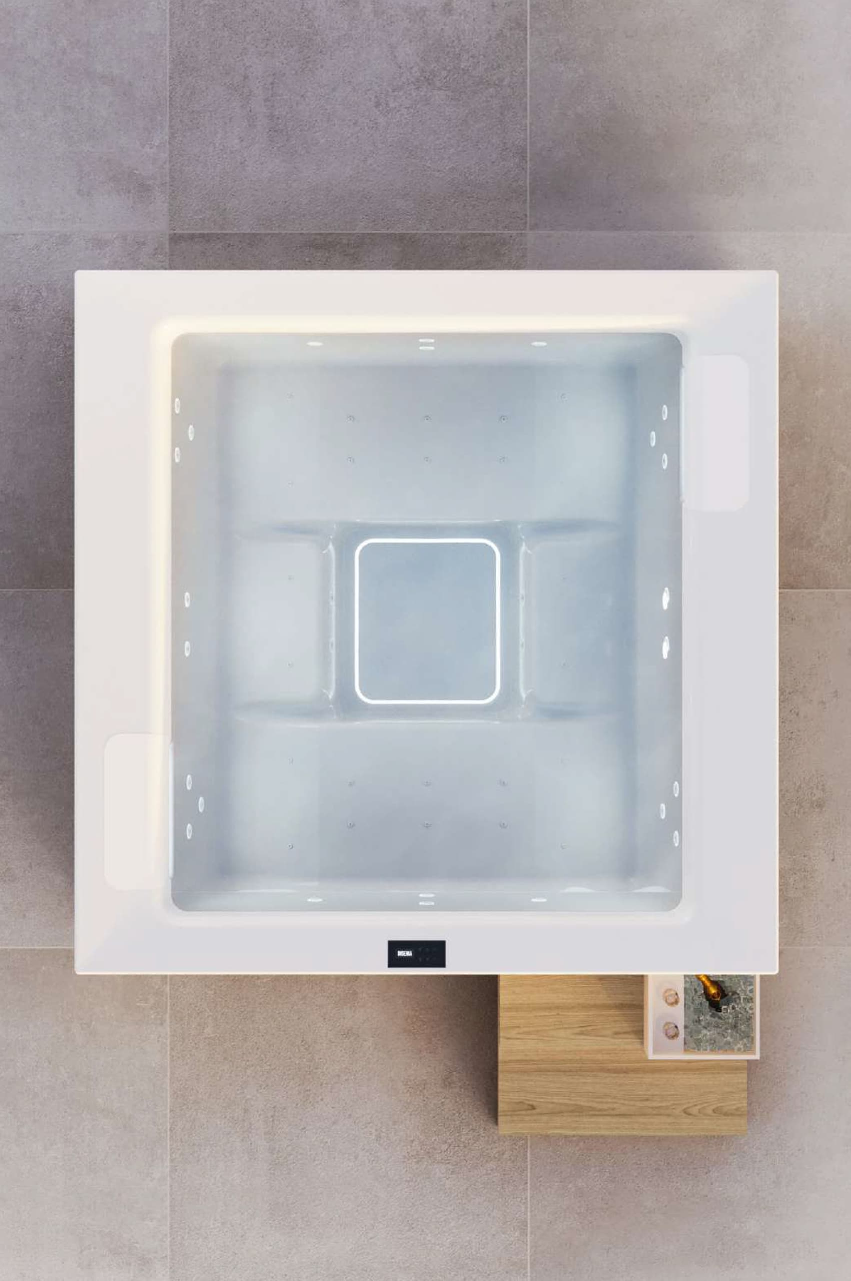 Ein quadratischer weißer Outdoor-Whirlpool "Gilium" mit LED-Beleuchtung, Massagedüsen und Holzstufen mit Champagnerkübel aus Vogelperspektive auf grauem XL-Fliesenboden von Disenia.