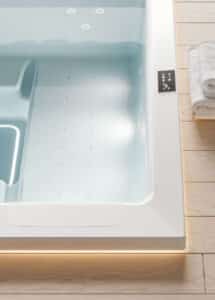Detailansicht des quadratischen weißen Outdoor-Whirlpools "Gilium" - hier in der Unterbauversion mit Touchscreen-Panel und beleuchtetem LED-Rand von Disenia.