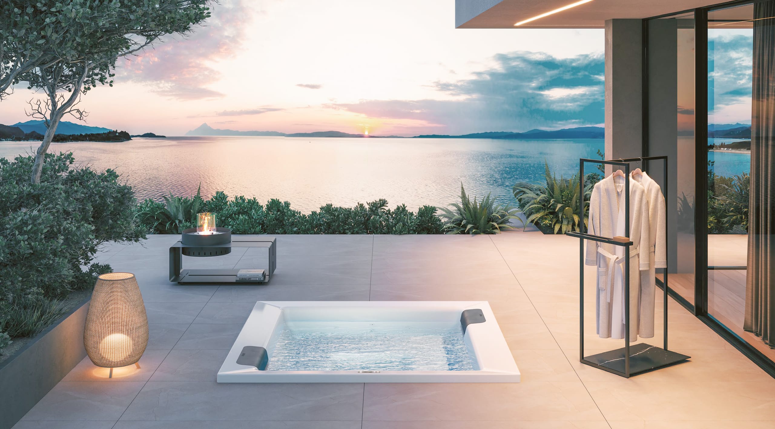 Terrasse mit XL-Steinfliesen und einer Unterbauversion des Outdoor-Whirlpools "Kyra" in Weiss mit schwarzen Nackenstützen bzw. Einstiegshilfen oder Sitzflächen am Rand mit matter Oberfläche und Touchscreen-Panel umgeben von einem stummen Diener, einer Stehlampe und einem Beistelltisch mit Feuerstelle von Disenia.