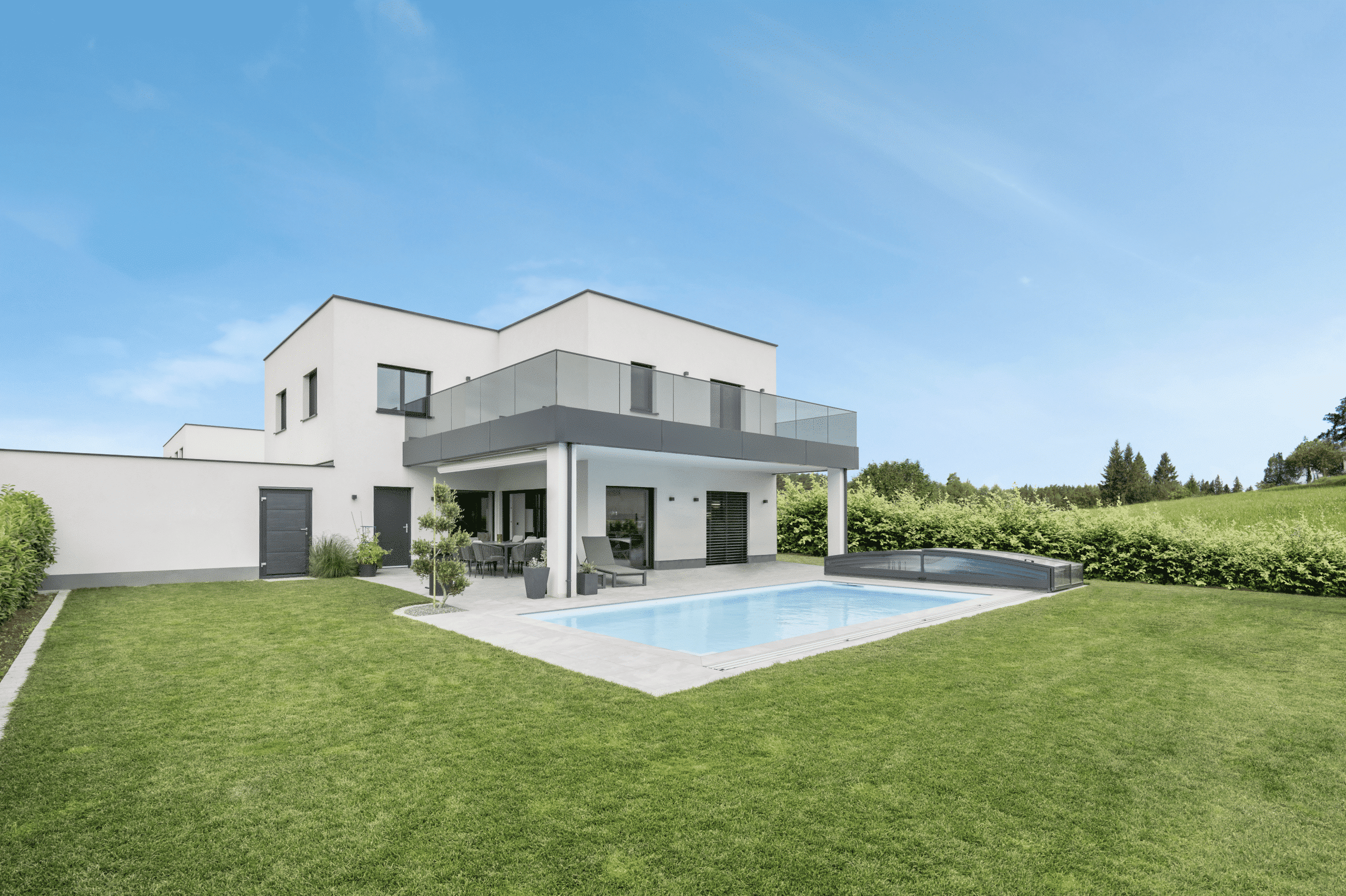 Modernes weißes Flachdach-Wohnhaus mit U-förmigem Glasgeländer-Balkon, Terrasse, Pool und dunkelgrauen Außentüren und Fenster mit dunkelgrauem Rahmen von Internorm.