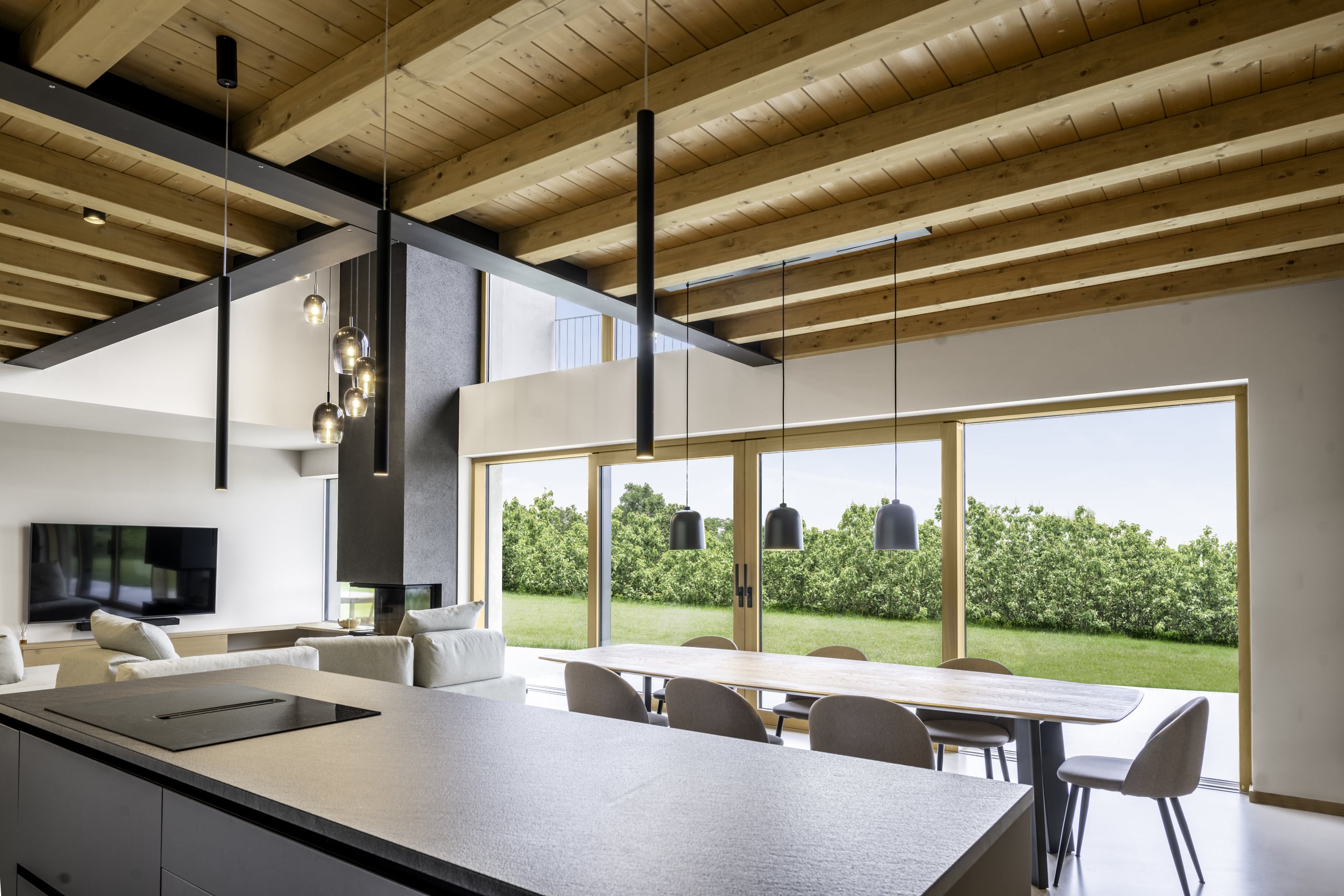 Helles Esszimmer mit Küchenblock, Holzdecke, raumhohen fix verglasten Fensterflächen und doppelten Glasschiebetüre von Internorm.