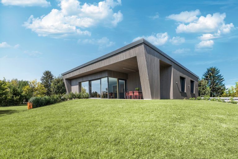 Internorm zeigt eine Villa mit moderner Architektur, Terrasse mit Ganzglassystem ums Eck mit schwarzem Rahmen.