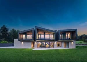 Internorm zeigt eine Villa mit moderner Architektur, Balkon, Terrasse mit Ganzglassystem mit schwarzem Rahmen.