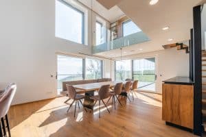 Internorm präsentiert einen lichtdurchfluteten Wohnraum mit Galerie, großen Fenstern und Glasschiebetür auf die Terrasse.