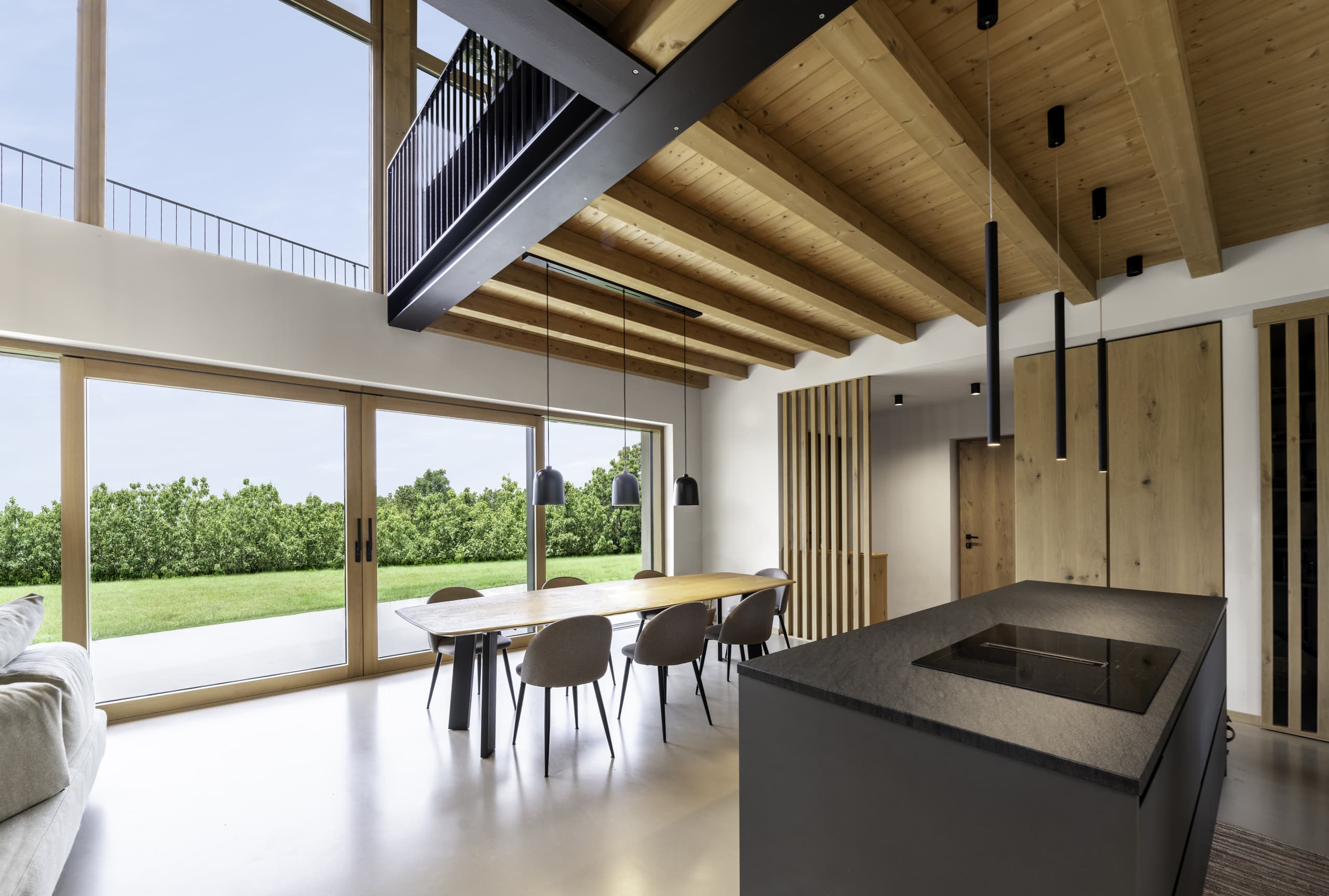 Internorm präsentiert einen offenen Wohnraum mit Galerie, großen Fenstern und Glasschiebetür auf die Terrasse.