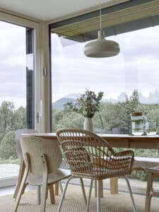 Ein Essbereich mit Eckverglasung und Terrassentür mit Holz‑Alu‑Rahmen und einer schmalen eckmontierten Fernbedienung für die Steuerung Sonnenschutz von Internorm.