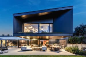 Eine moderne Villa mit überdachtem Terrassen- und Balkonbereich mit Schiebetüren und Fixverglasungen in schwarzem Alu-Rahmen von Internorm.