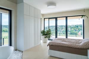 Ein Schlafzimmer mit großflächigen Terrassenschiebetüren und Glaselementen mit schwarzem Alurahmen von Internorm.