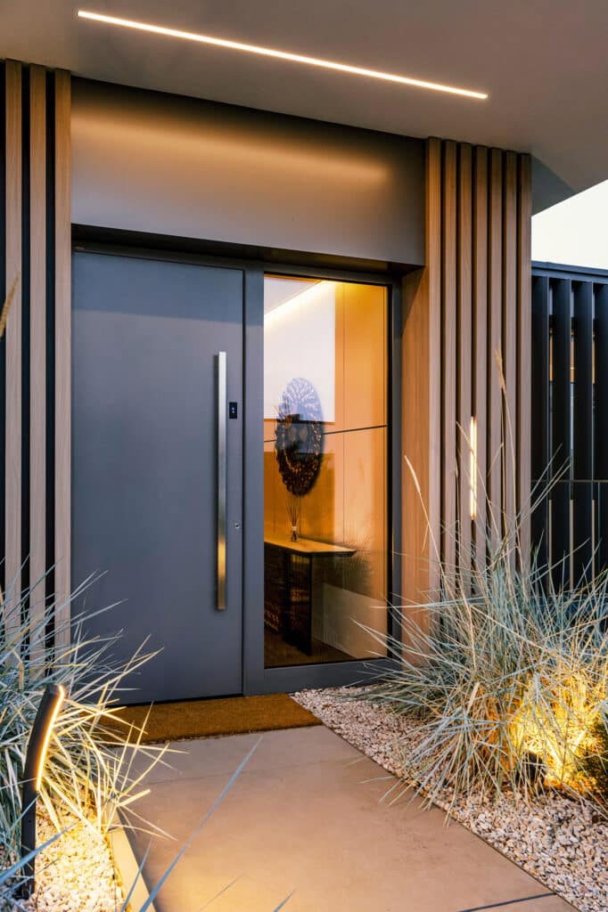 Moderner Hauseingang mit anthrazitfarbener Eingangstüre mit Seitenlicht und moderner Fassadengestaltung mit Holzsprossen und Lichtstreifen von Internorm.