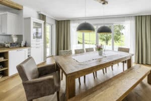 Essbereich und Wohnküche im rustikalen Landhausstil mit klassischen weißen Hebeschiebetüren und Terrassentüren im Sprossenlook von Internorm.